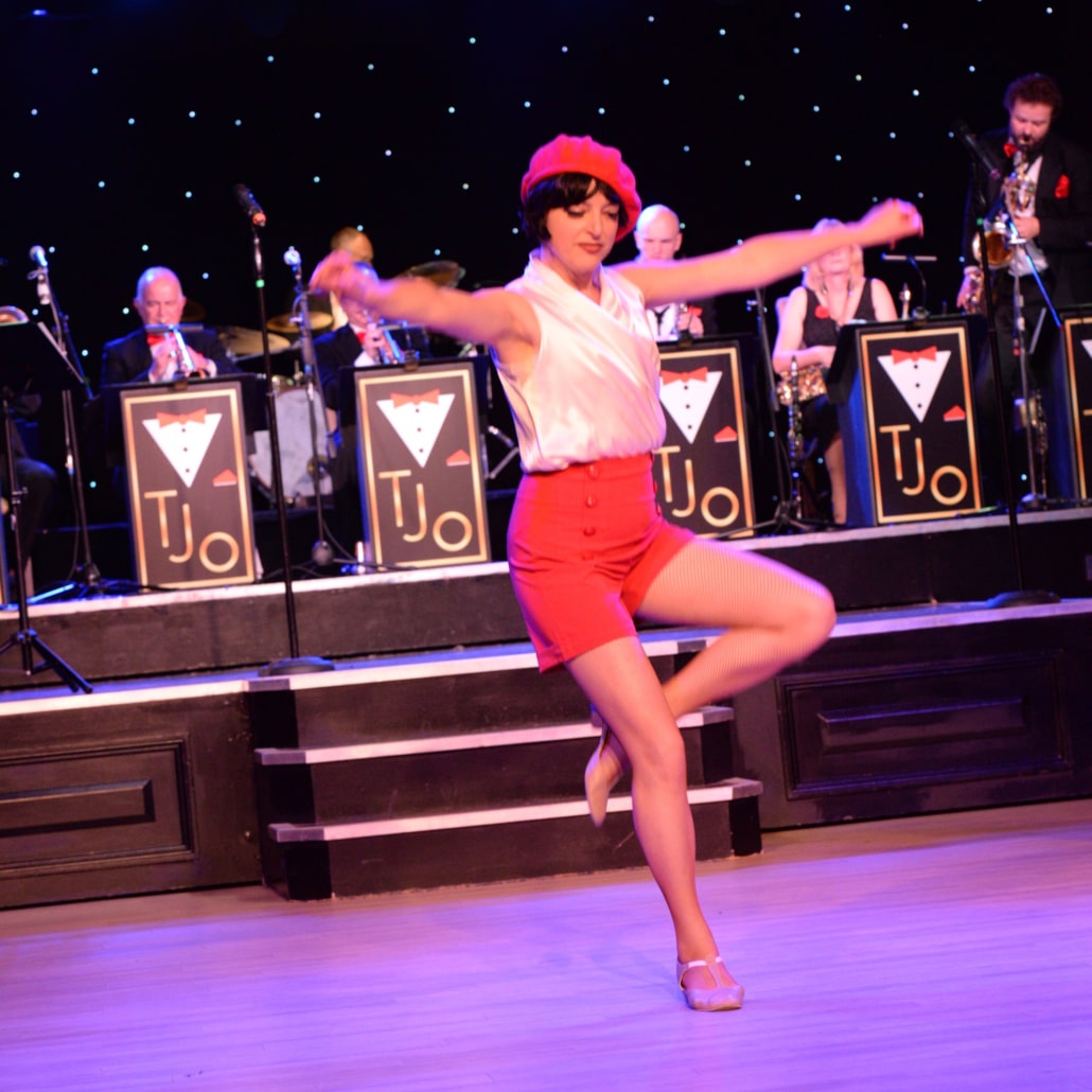 Picture of a TJO Dancer with the orchestra in the background